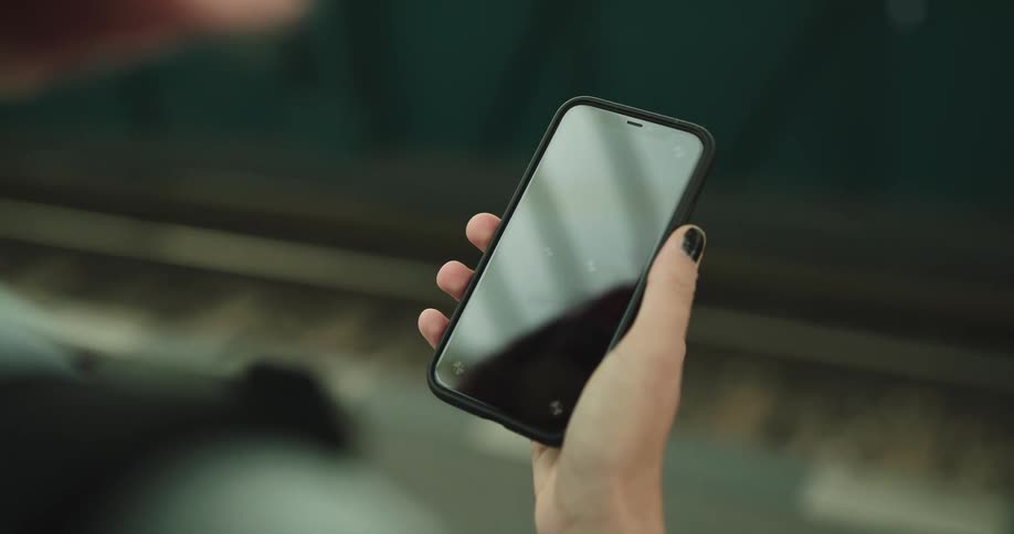 A girl is texting on a cellphone and standing outdoors