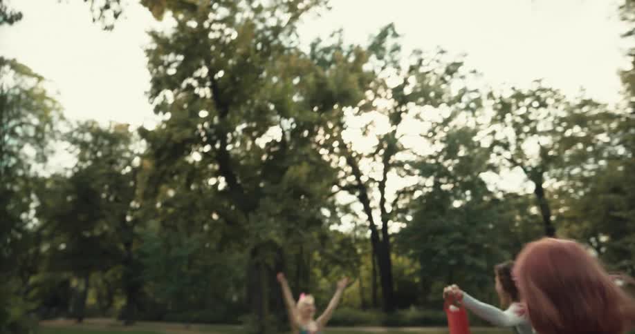 A group of women celebrate and dance around in a grass setting