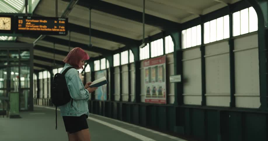 A woman reads a book while waiting for the train