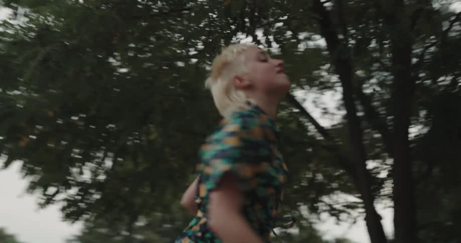 A woman is dancing on a bench in a park in front of people