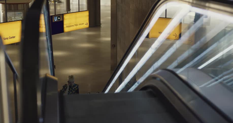 A woman talks on the phone while walking up an escalator in an office building