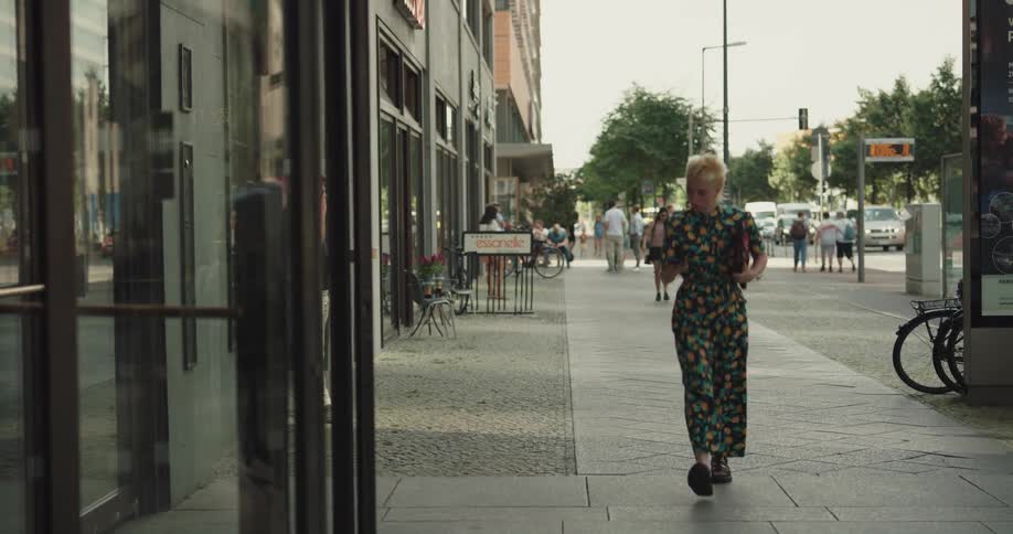 A young woman walking along a sidewalk in a city enters a building