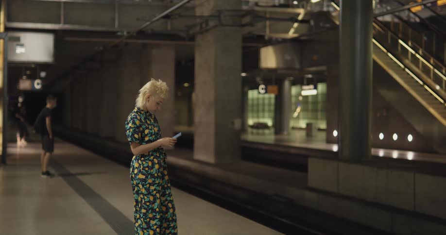 A woman is checking her phone while waiting for the train