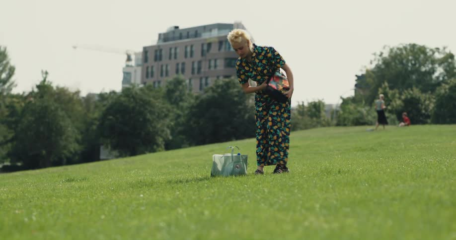 A woman walks in the park and sits down