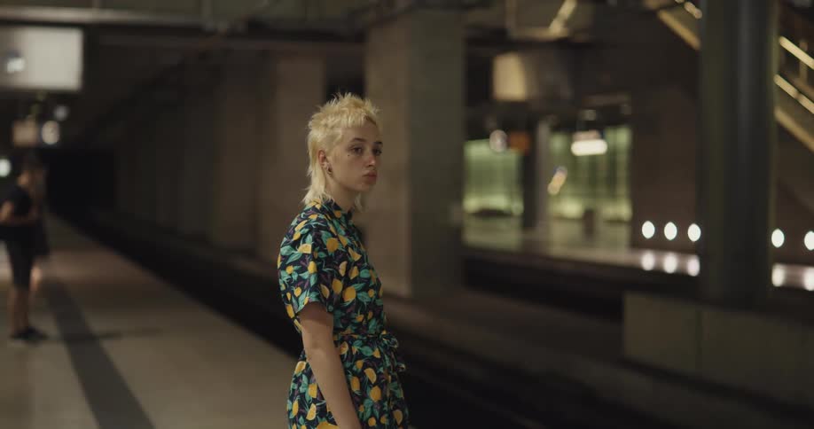 A teenager stands on a platform while waiting for a train