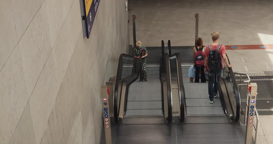 People are riding an escalator up and down in a train station