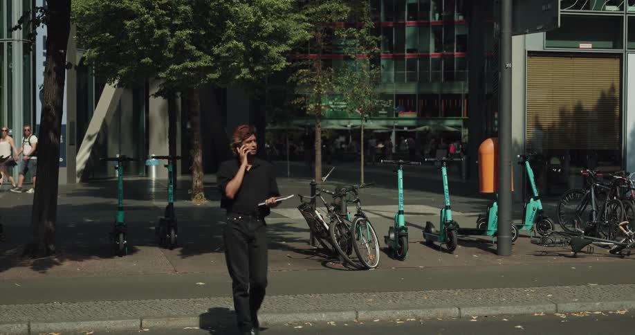 A man talking on a cellphone crosses a busy city street