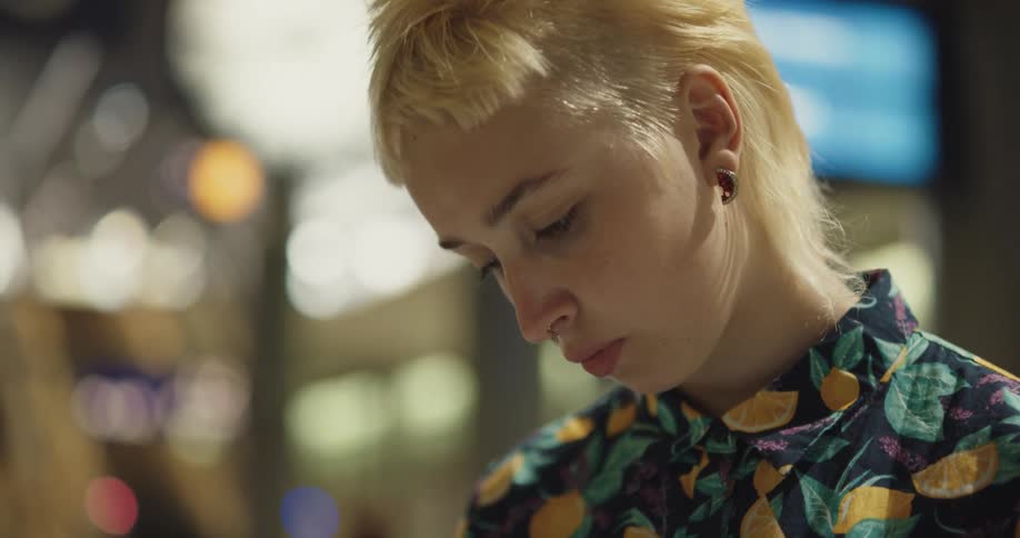 Blonde woman stands in transit station looking around