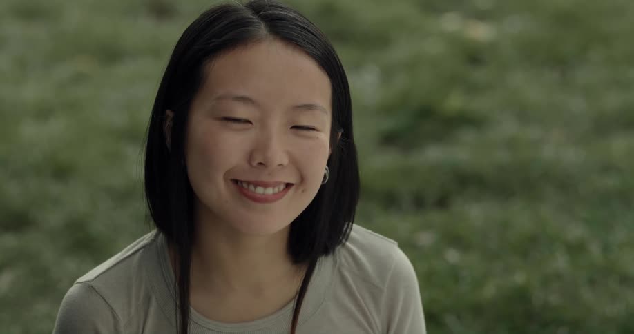 A woman is sitting on a grassy field and smiling