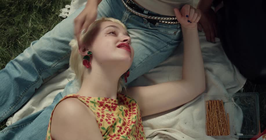 A woman lays on the picnic blanket with a friend