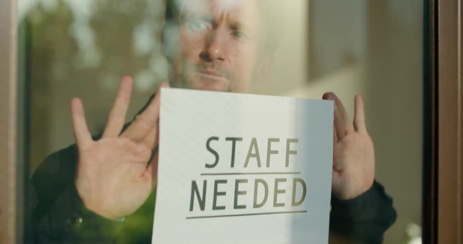 Man post help wanted sign in business window