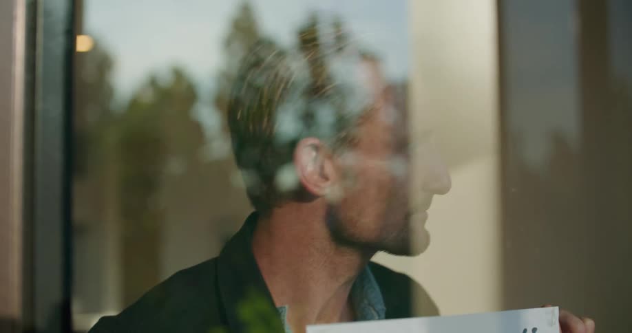 Man posts help wanted sign in window and smiles while looking through the glass