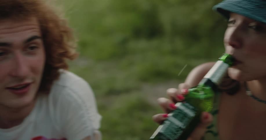 A man is talking while a girl drinks beer