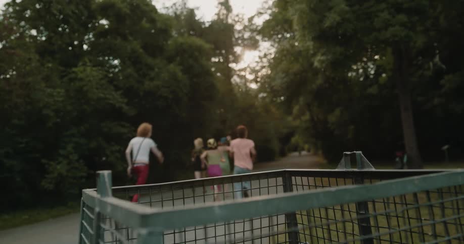 A group of people place a garbage bag into a trash bin before running off down a trail together