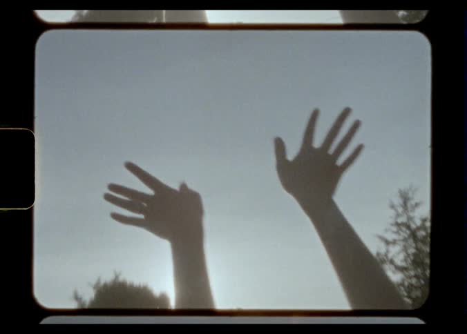 Woman is silhouetted against the sun dancing and moving hands