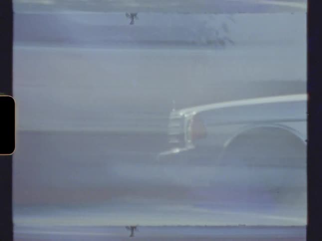 Vehicle parked in the curb of a busy city street at morning caught on vintage film