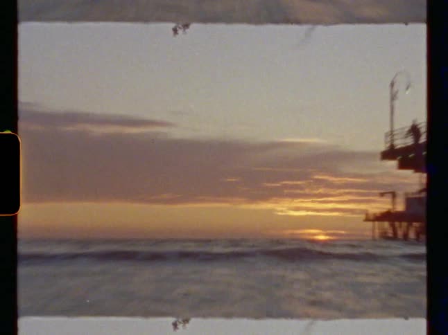Film footage of ocean waves moving towards the coast at dusk