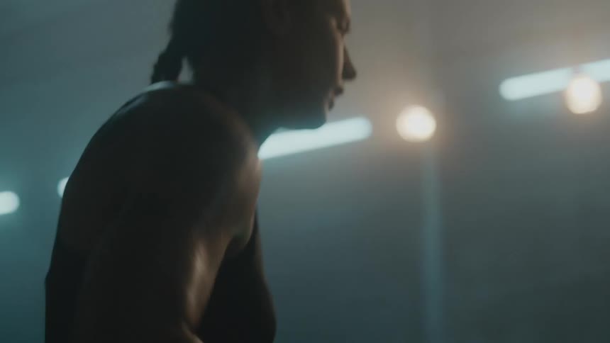 Female boxer with braids hits a punching bag and shakes her arms