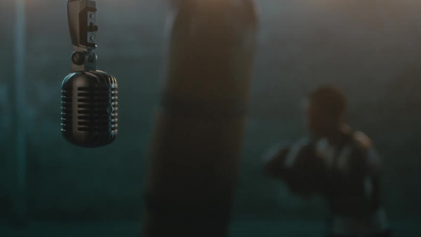 A microphone is hanging near a woman punching a heavy bag