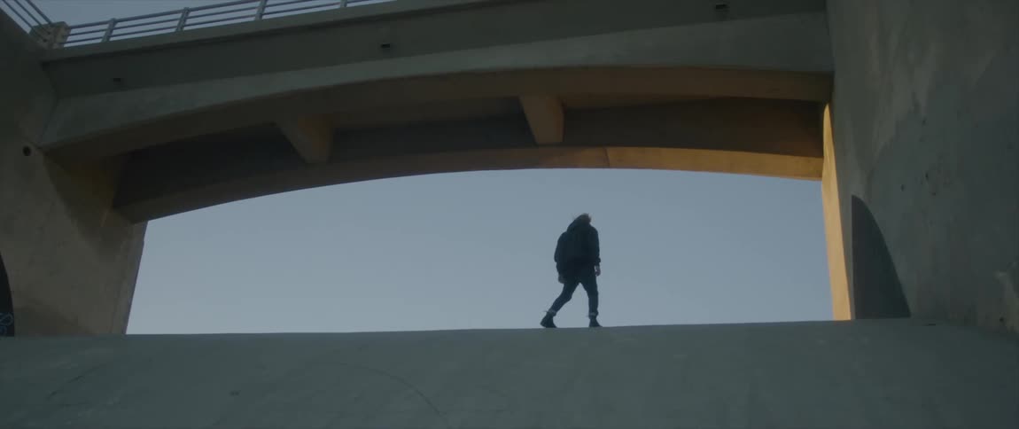 A man is walking under the overpass