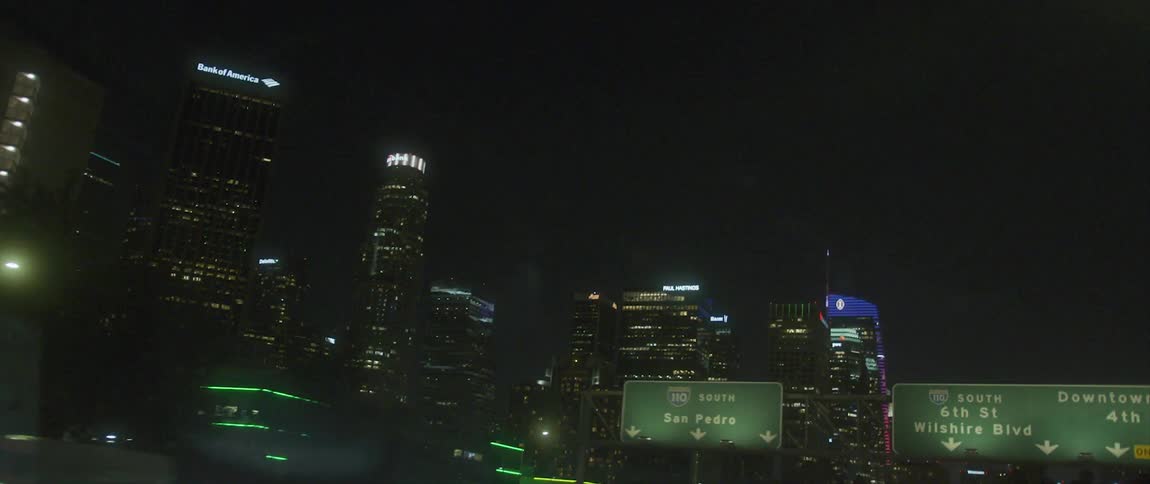 Skyscrapers loom over a highway through a metropolis at night