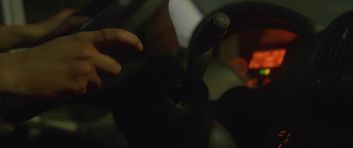 Close up of the hands of a woman over the steering wheel of a car driving at night