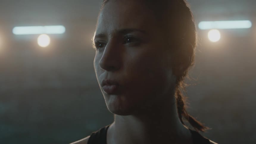 A woman stands in a dim room with brick walls