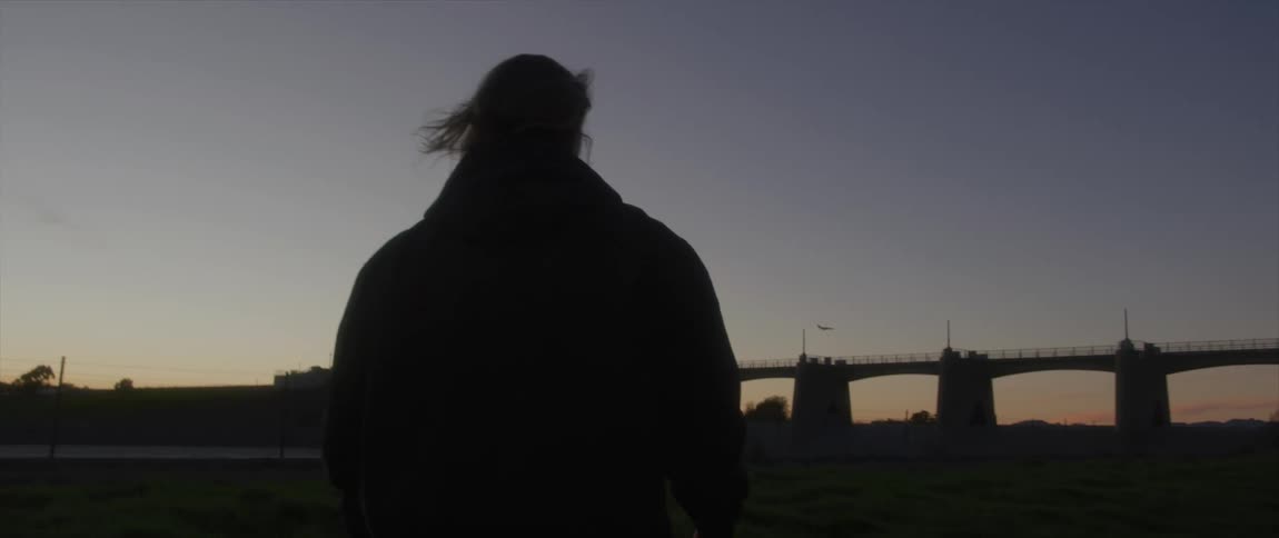A person is walking outdoors while the sun is setting