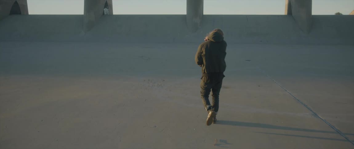 A man is walking towards a bridge in a city