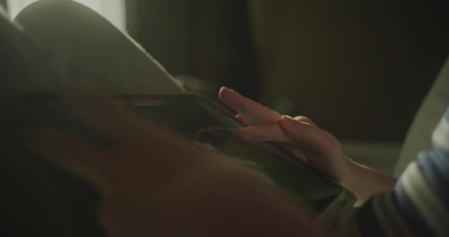 Young teenage boy playing video games on a tablet while sitting on the couch at home