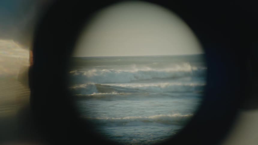Ocean waves breaking and splashing viewed through the round lens of a telescope