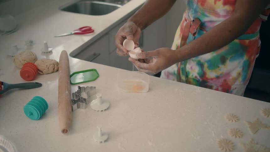 Man cracking an egg into a container while baking
