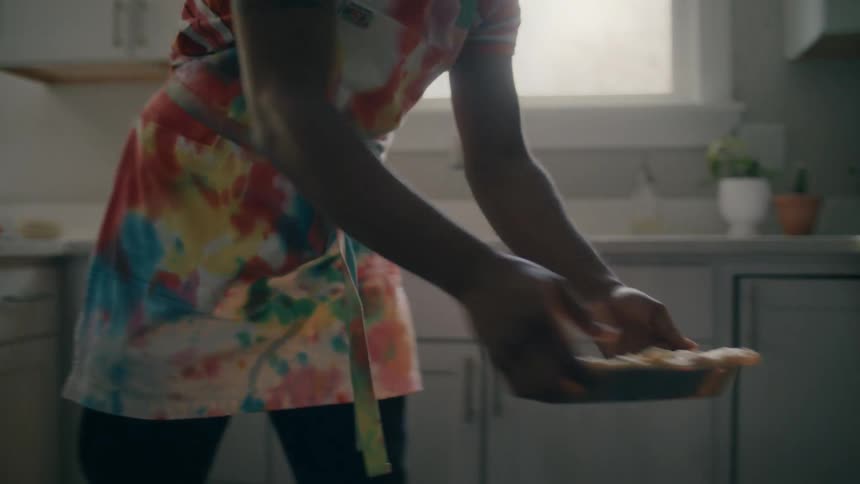A man at home opens the oven and puts a pie in and shuts the oven door