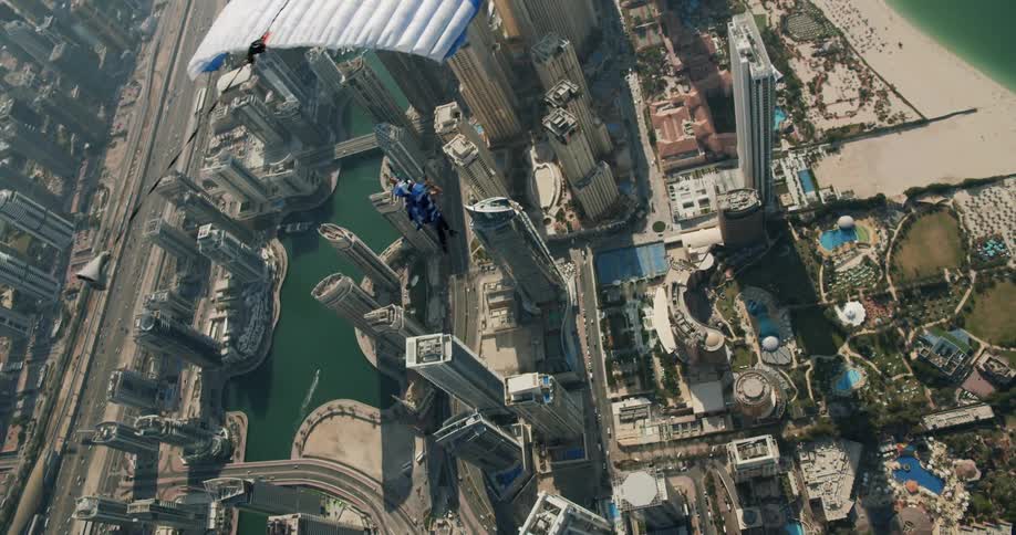 A skydiver floats above the city skyscrapers near the beach and ocean shore