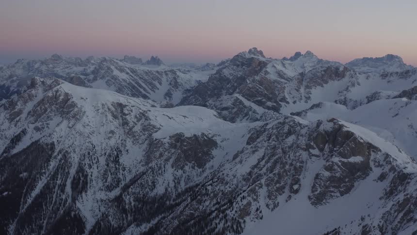 Aerial view of the snow covered peaks of a mountain range at evening