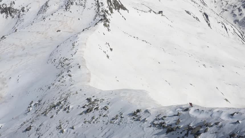 A skier skis along the top of a mountain ridge during the day