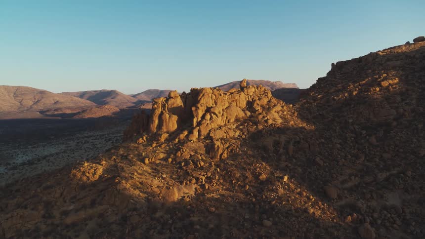 Aerial over desert rock formations at golden hour