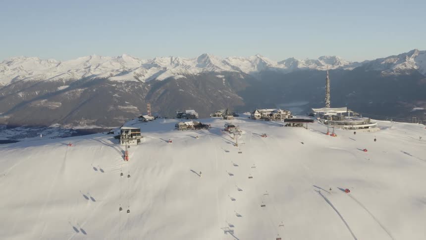 A long skier starts down the mountain near a bunch of buildings