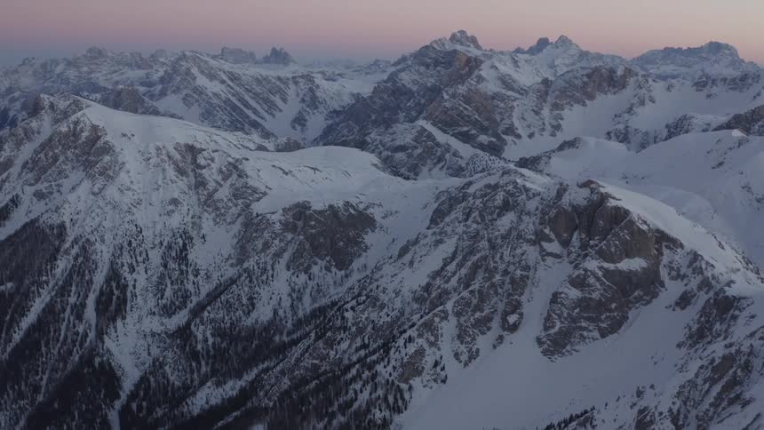 A snow covered mountain range in the evening