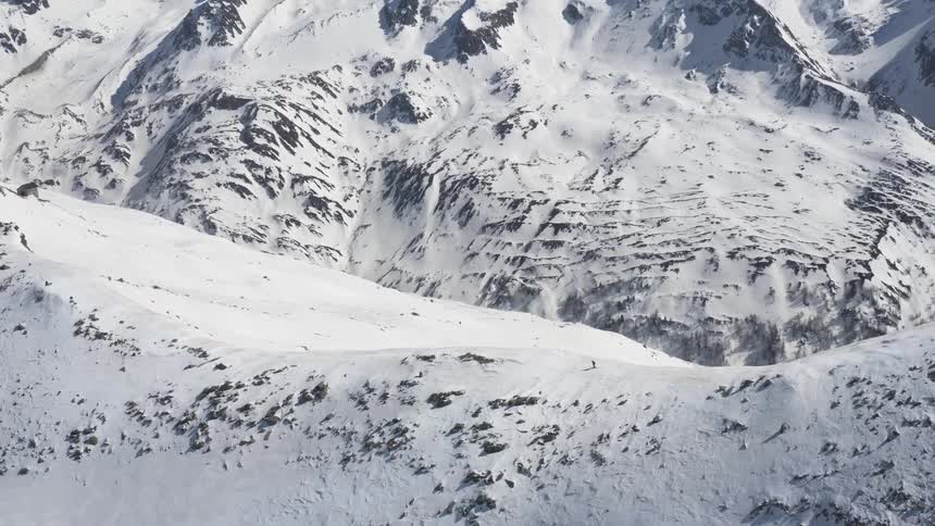 A person is skiing down the ridge of a snow covered mountain