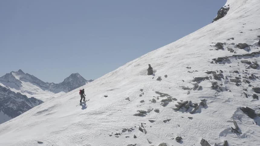 A person on skis hikes up a snowy mountain