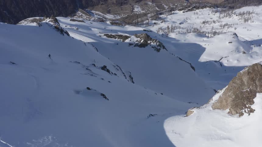 A person skies down the snow covered slopes of a mountain in winter