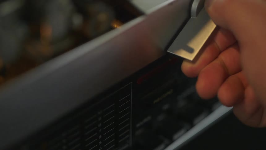Close up of a hand pushing a button and turning a knob on a machine