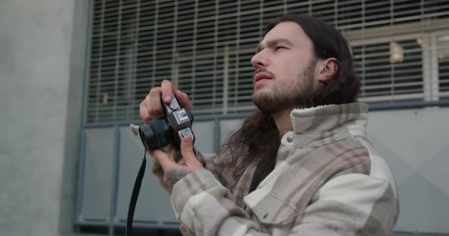 A photographer takes a photograph while standing outdoors before turning to look behind himself