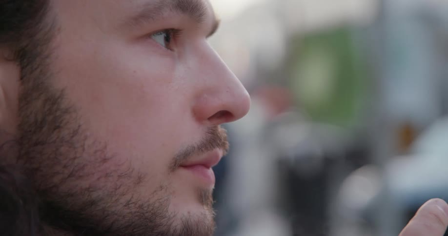 Man looks around while standing outdoors drinking form to go cup