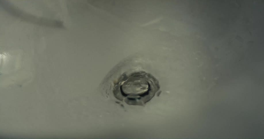 Water is running down and draining out in a sink drain