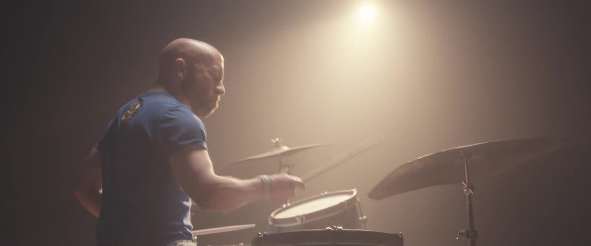 A man is playing the drums under the spotlight