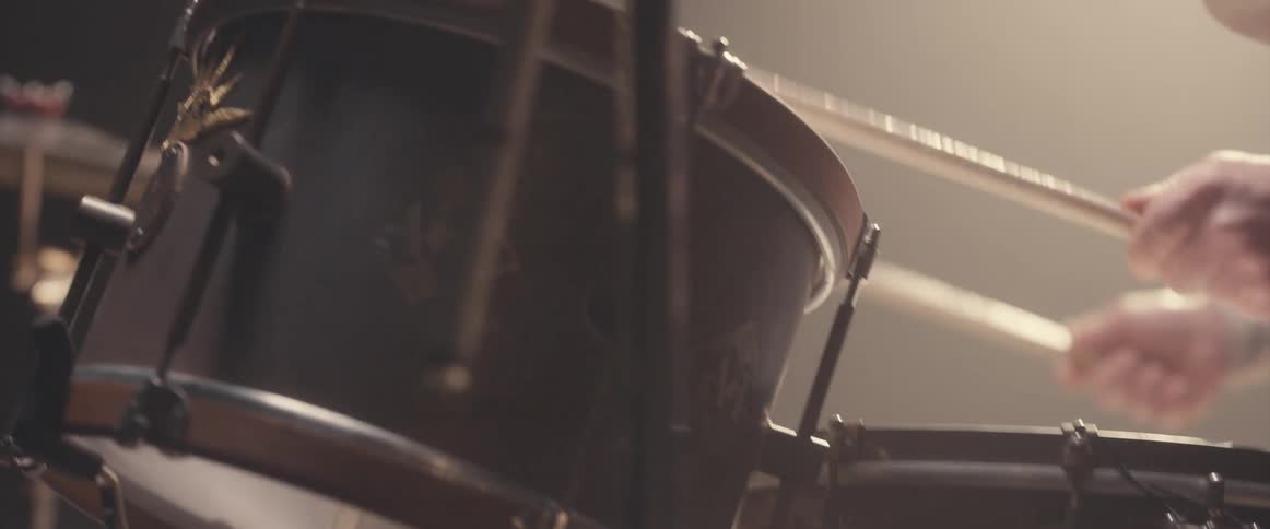 A drummer plays the drums in a dark place