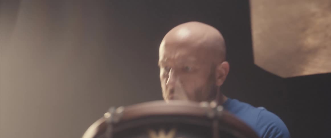 A light shines down on a man playing the drums