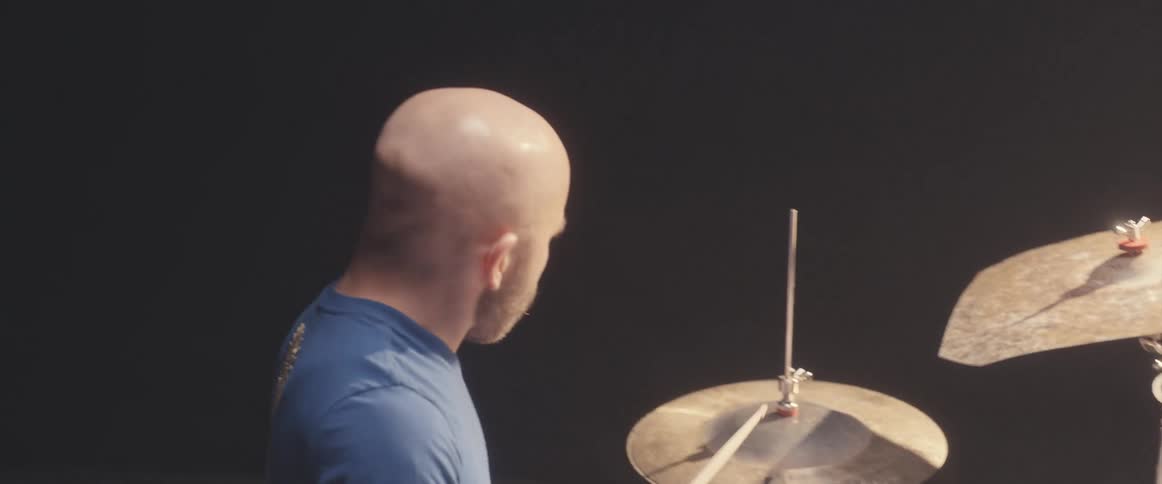 A man seems to practicing drums in a studio